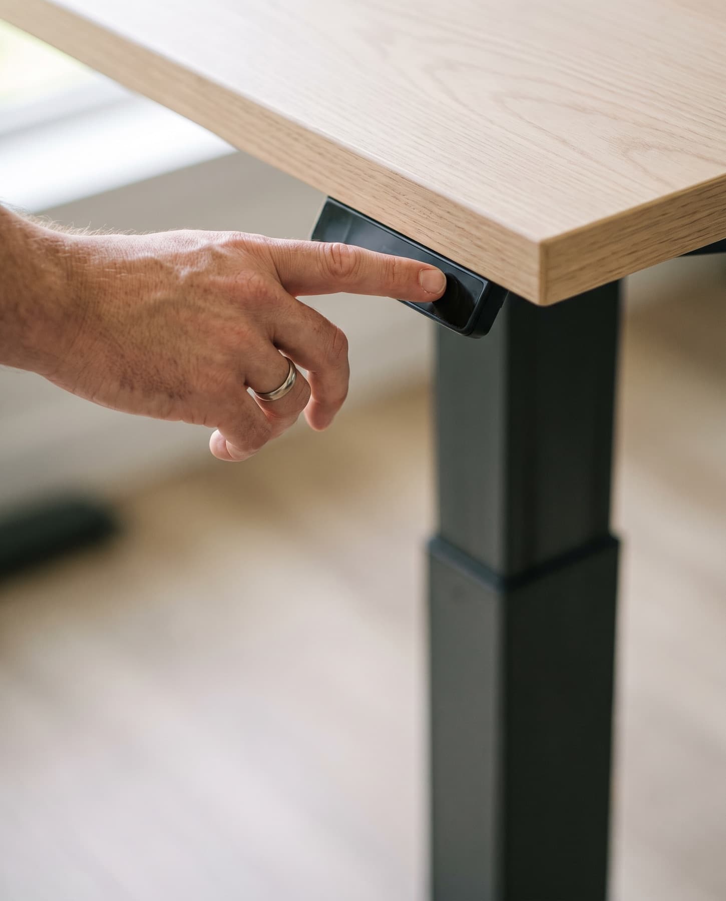Main posée sur le panneau de commande tactile d'un bureau assis-debout, colonne télescopique en mouvement